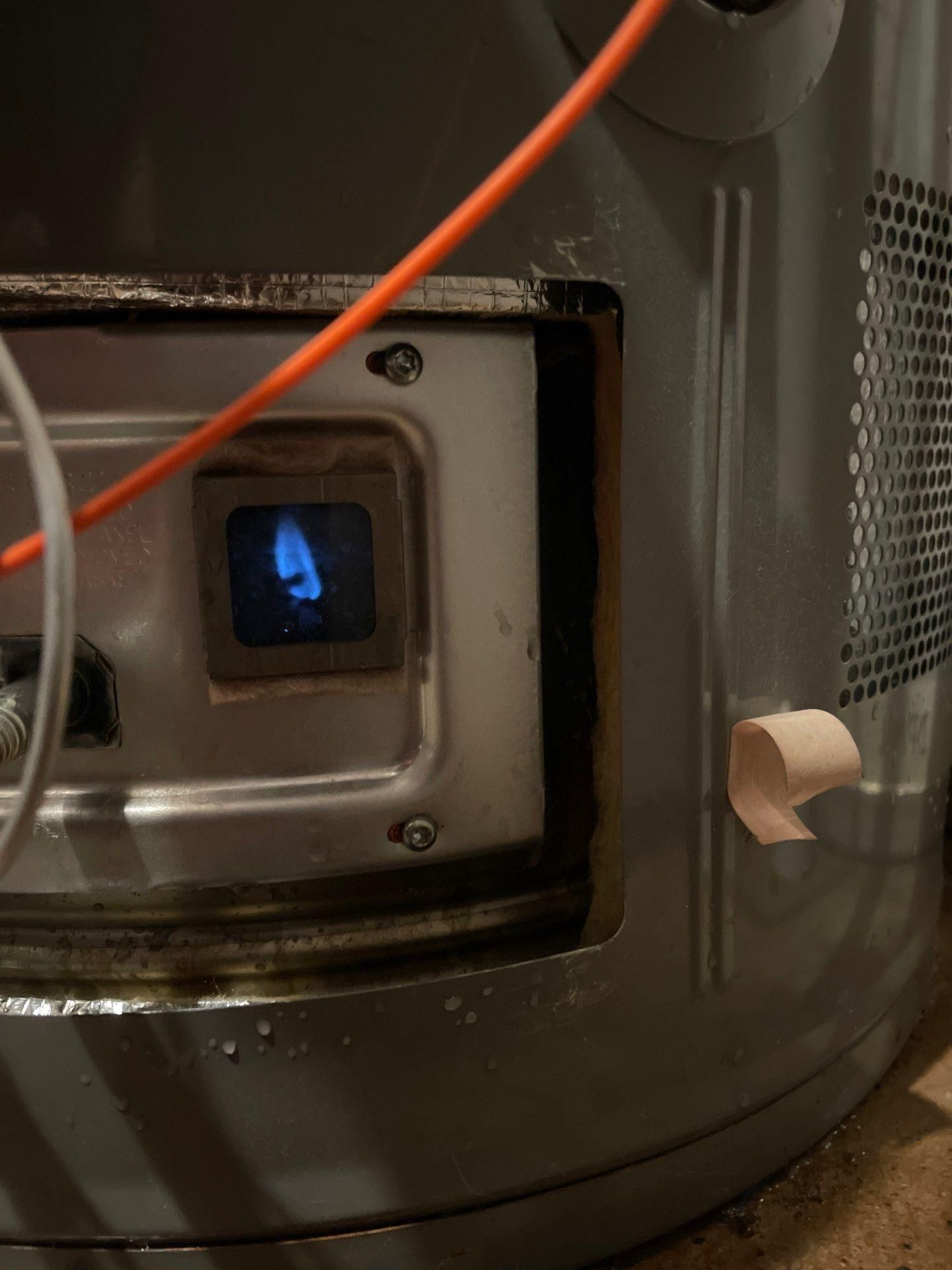 Close-up of a metal appliance with a small blue-lit window and an orange cable attached