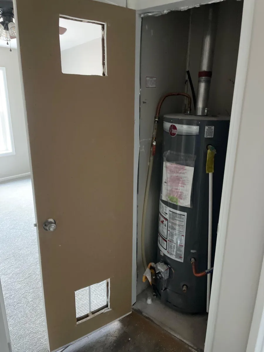 Open door revealing a water heater in a narrow utility closet