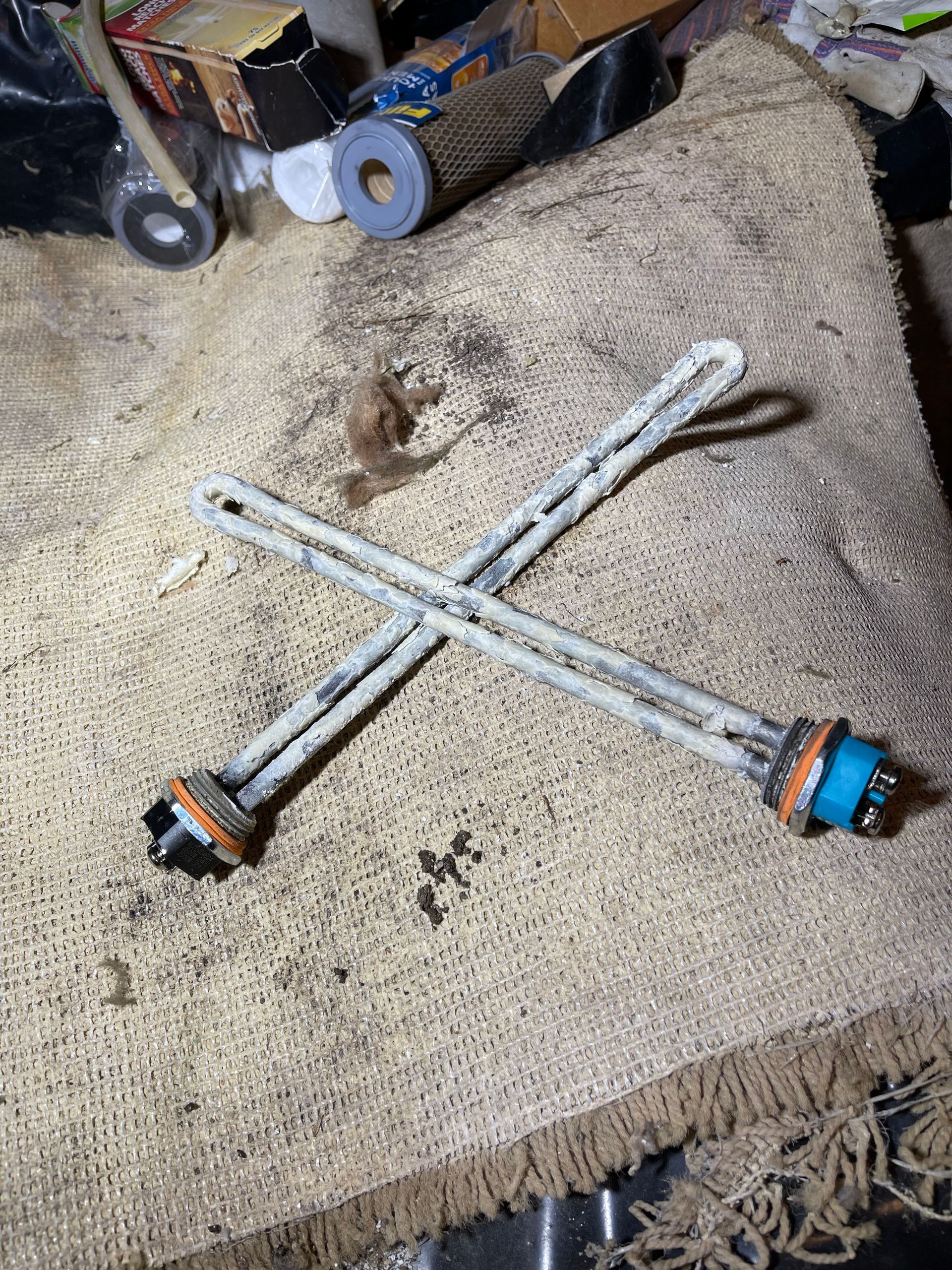 Two crossed metal rods with blue and orange end caps lying on a beige carpet.