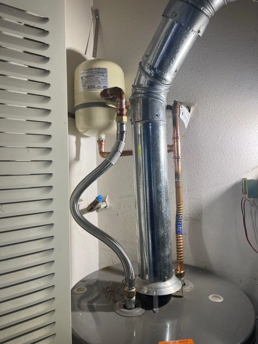 Water heater with metal vent pipes and hoses in a utility closet