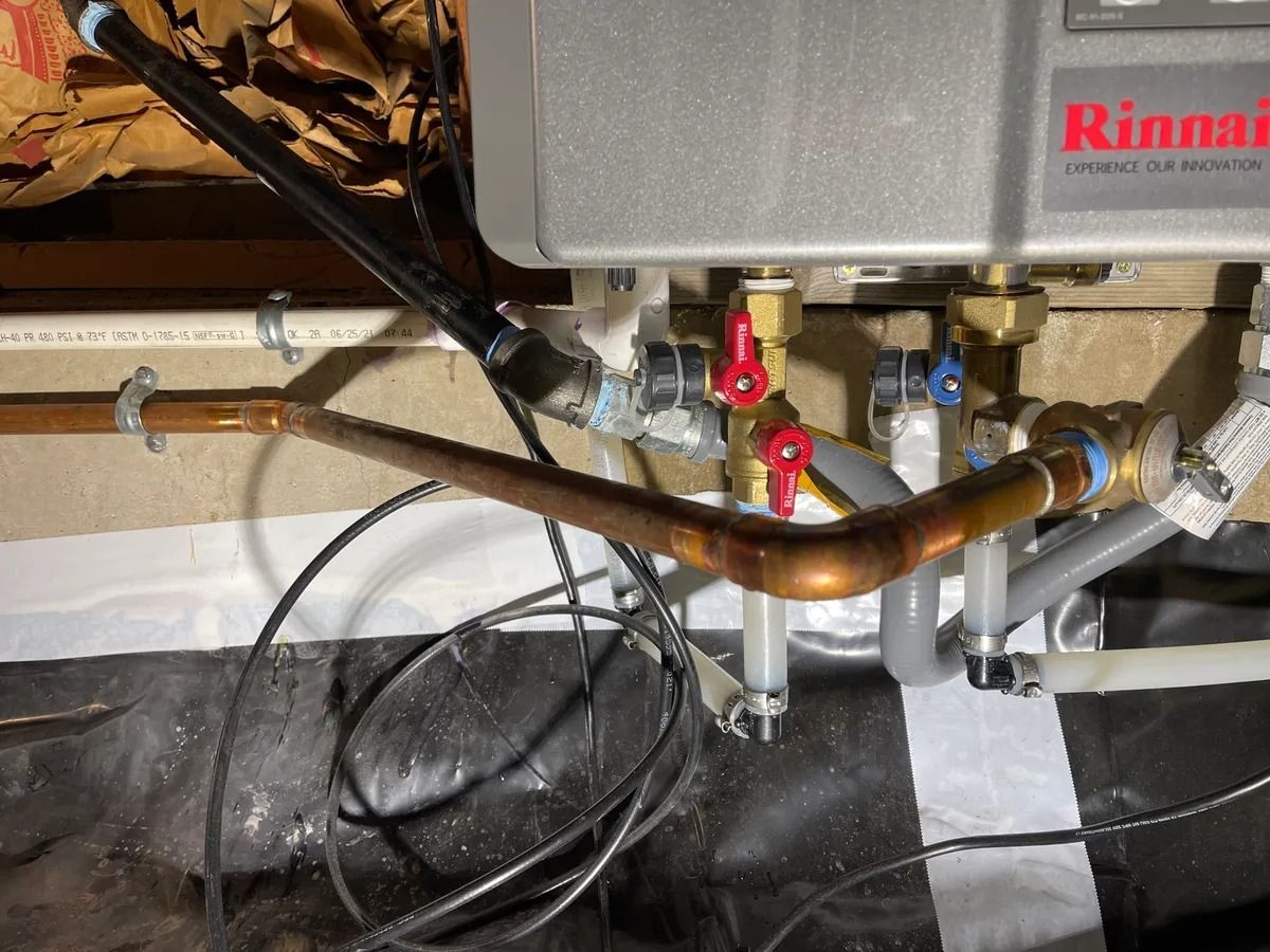 Rinnai water heater with copper pipes, valves, and wiring in a utility space