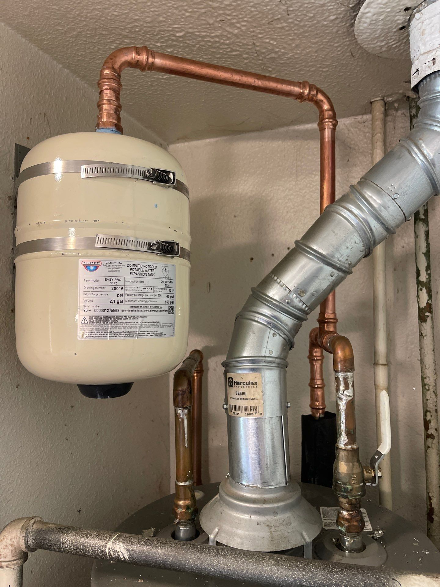 Basement utility area with a water heater, copper piping, and a metal vent pipe.