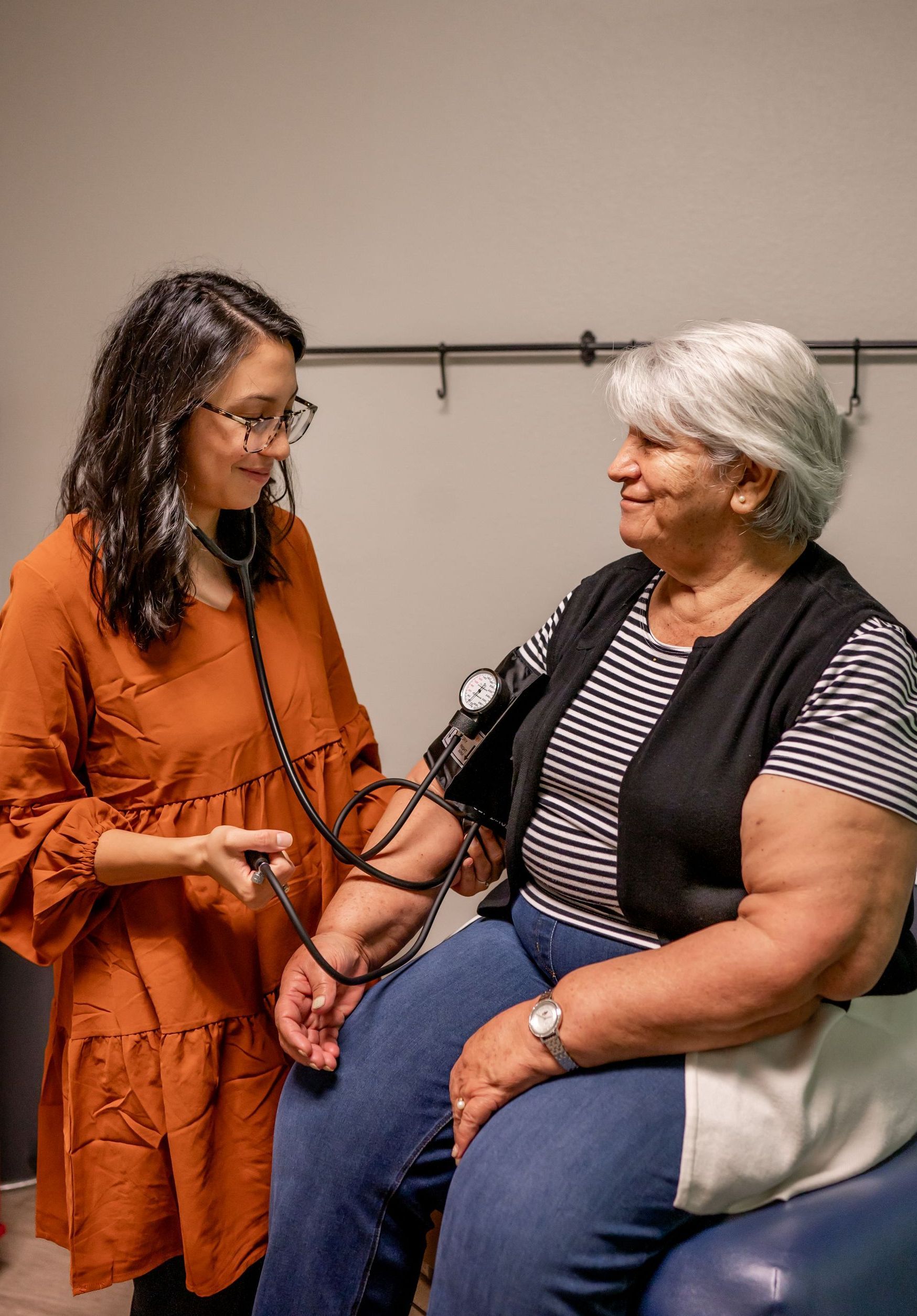 nurse practitioner using a stethoscope to check a woman's blood pressure