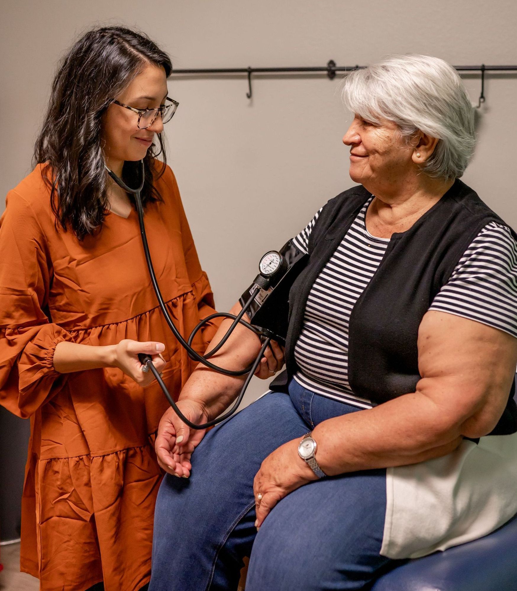 nurse practitioner using a stethoscope to check a woman's blood pressure