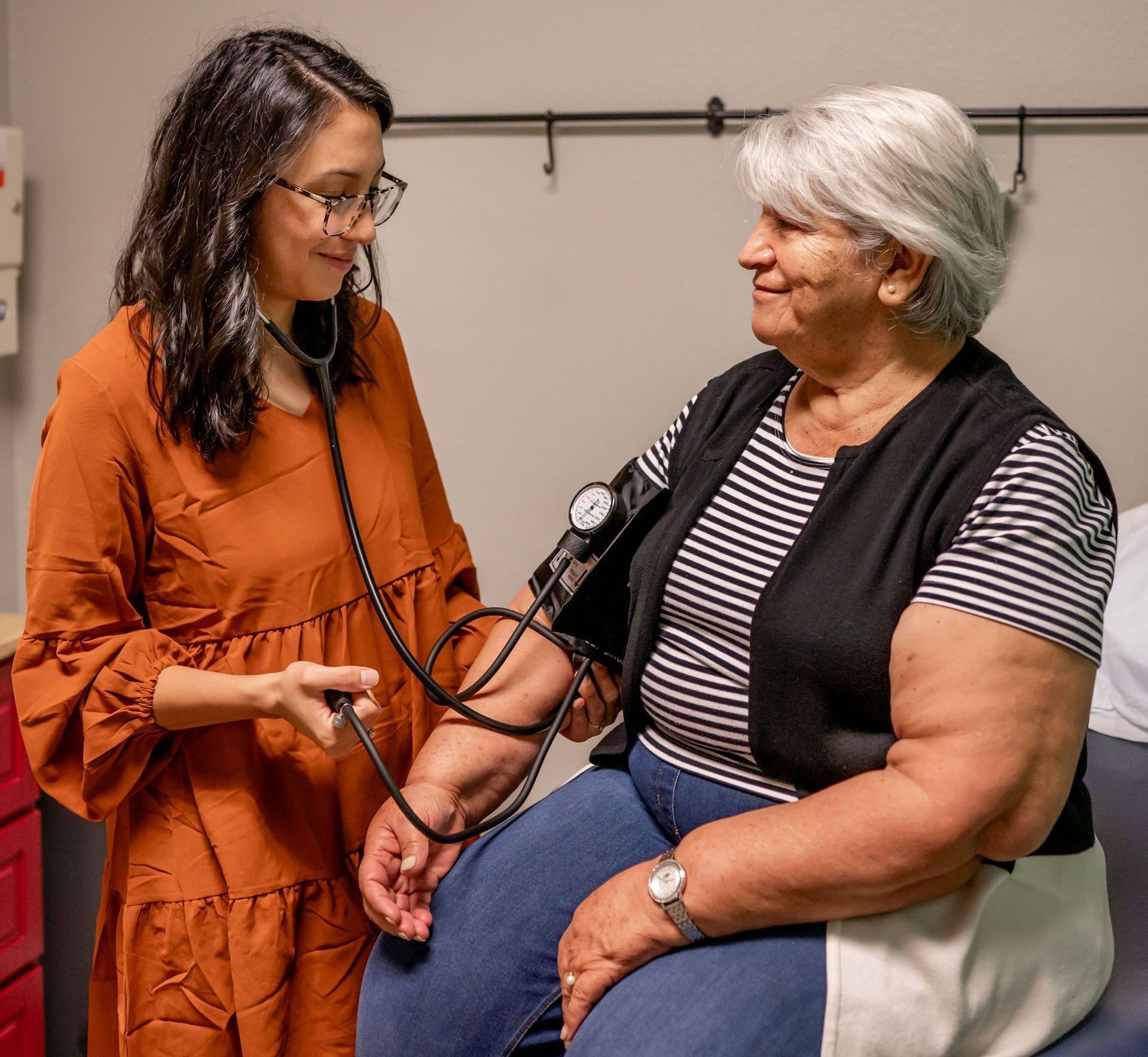nurse practitioner checking a woman's blood pressure using a stethoscope