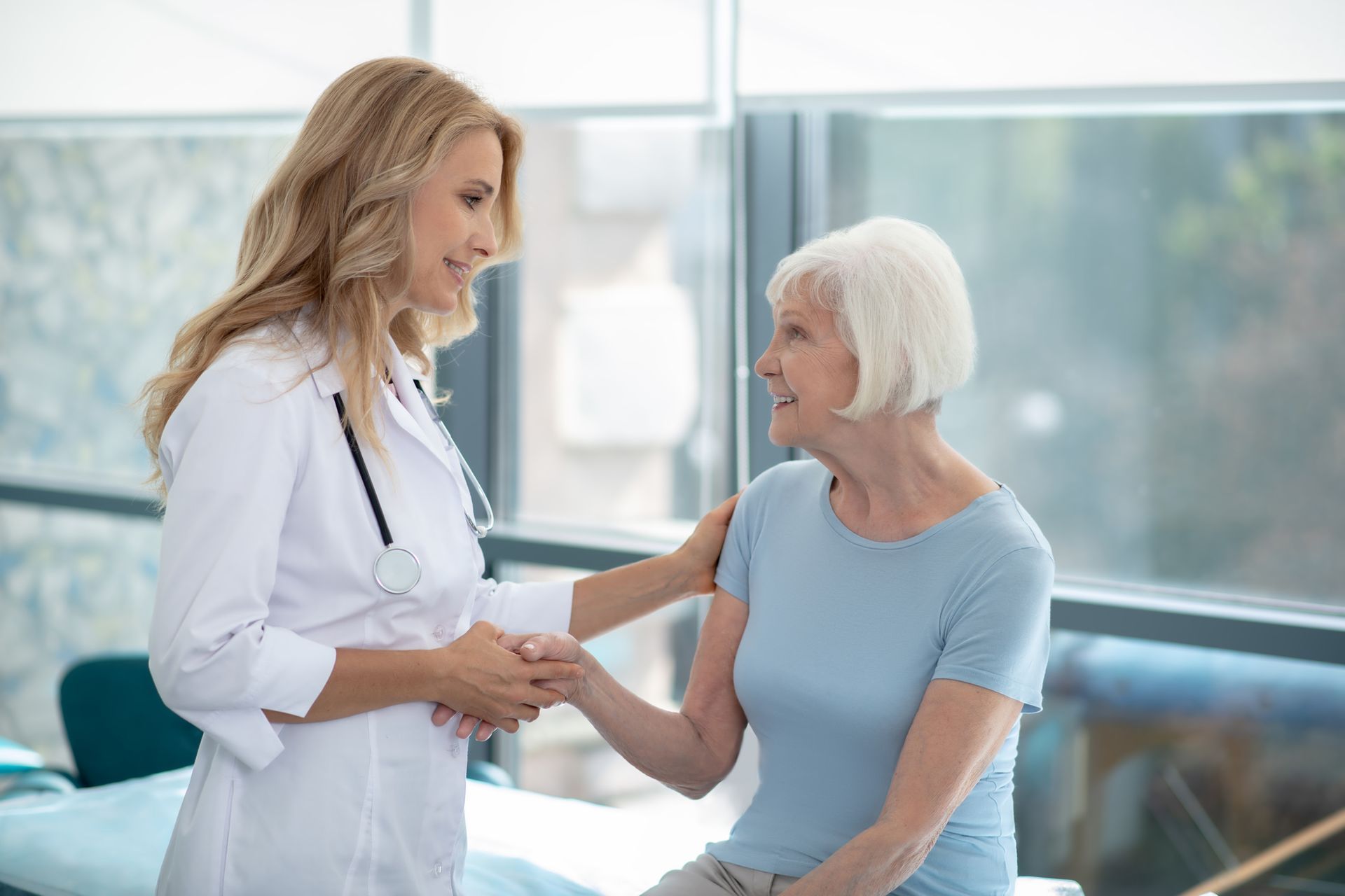 A doctor is talking to an elderly woman in a hospital room.