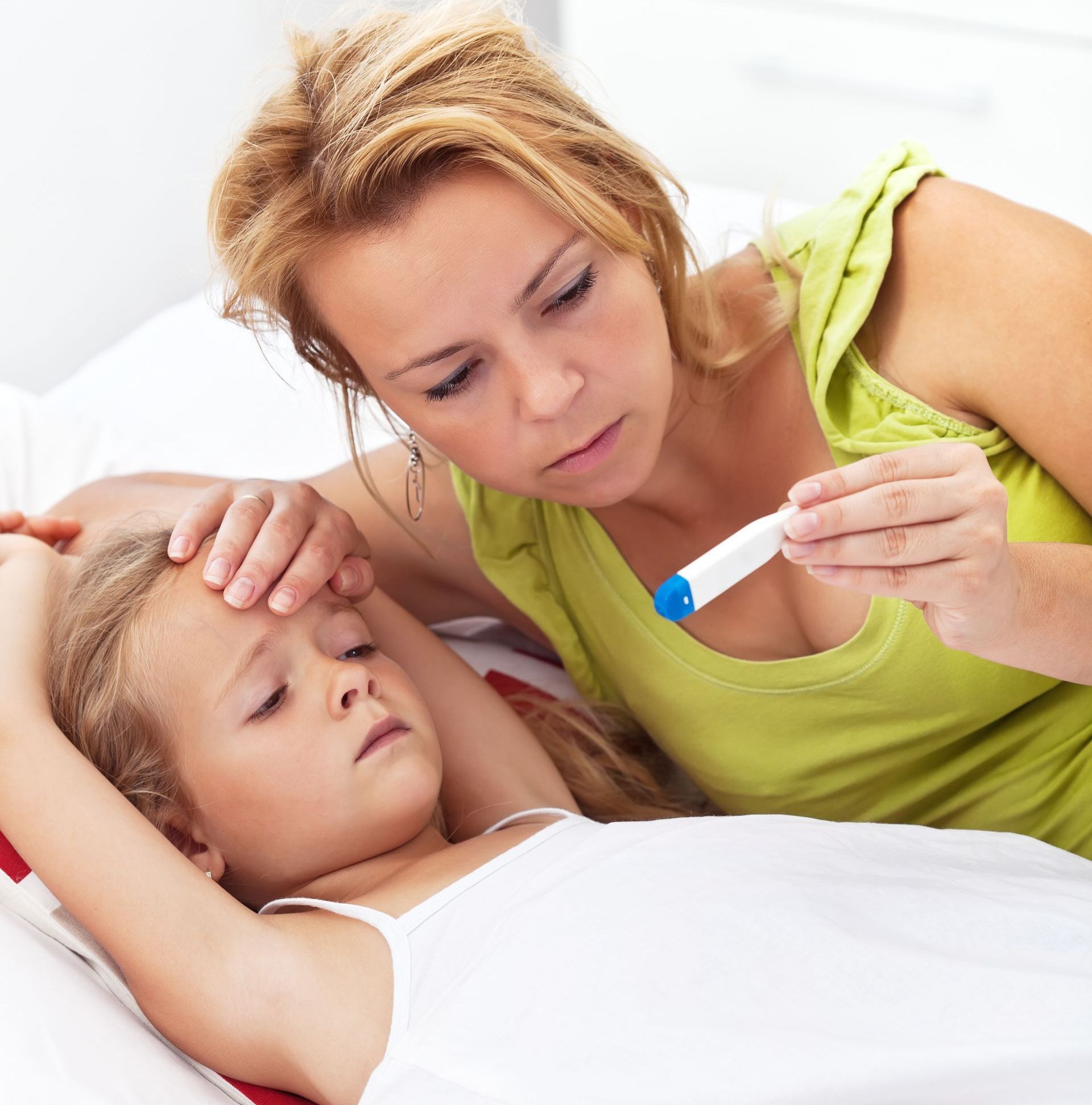 A woman is taking a child 's temperature with a thermometer