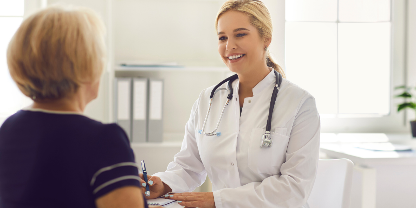 Provider smiling and talking with a medicare patient in a bright clinic office
