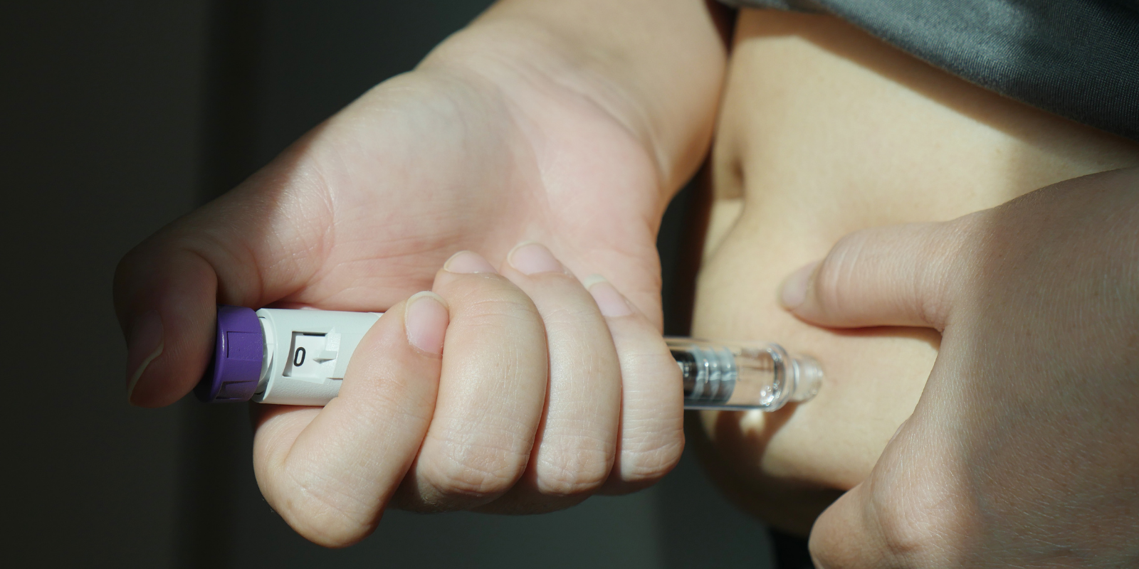 Hand holding a syringe injecting clear liquid into skin, close-up