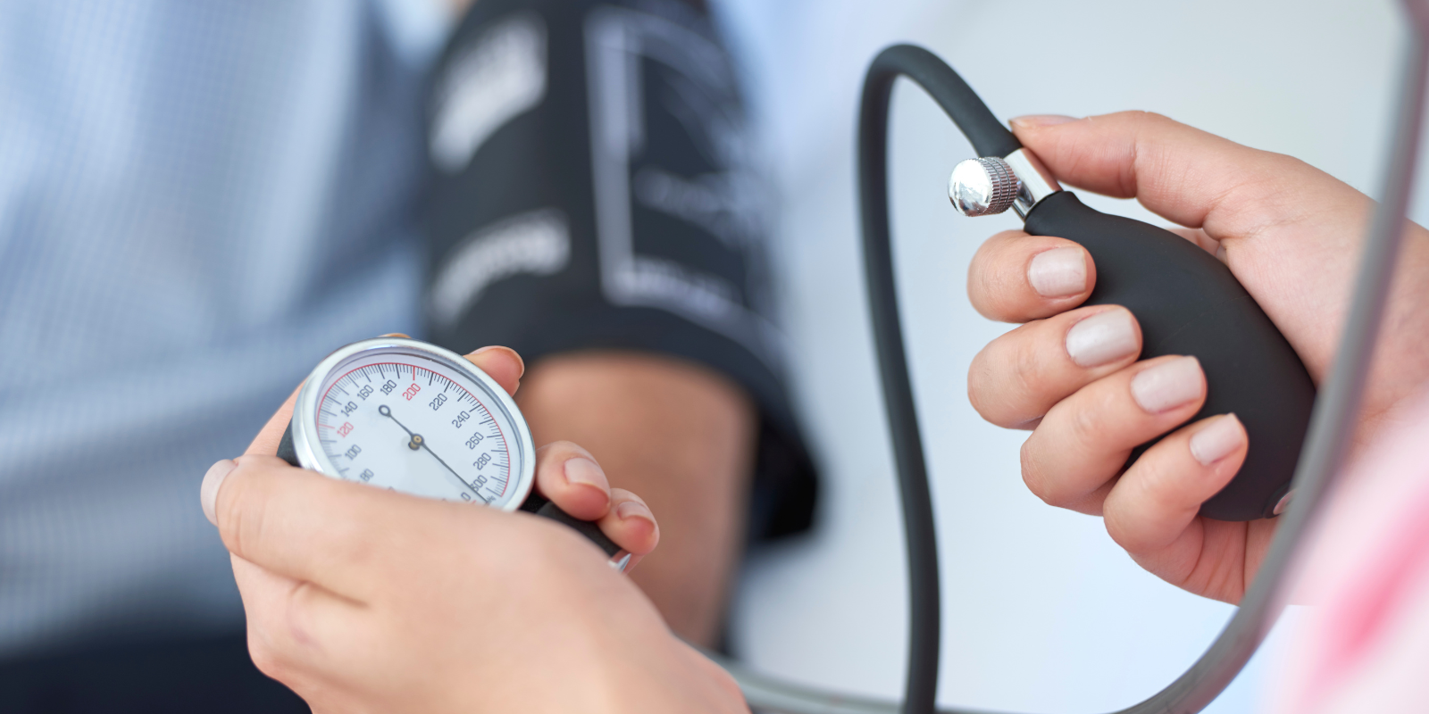 Doctor taking blood pressure with a cuff and gauge on a patient’s arm
