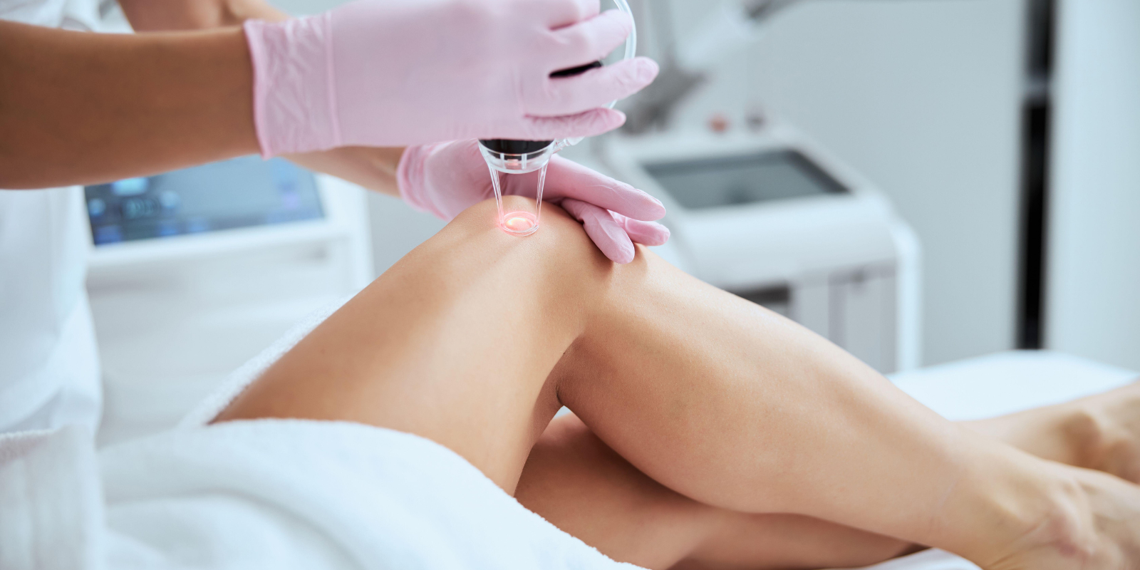 Gloved clinician applying a handheld device to a patient’s thigh in a medical spa treatment room