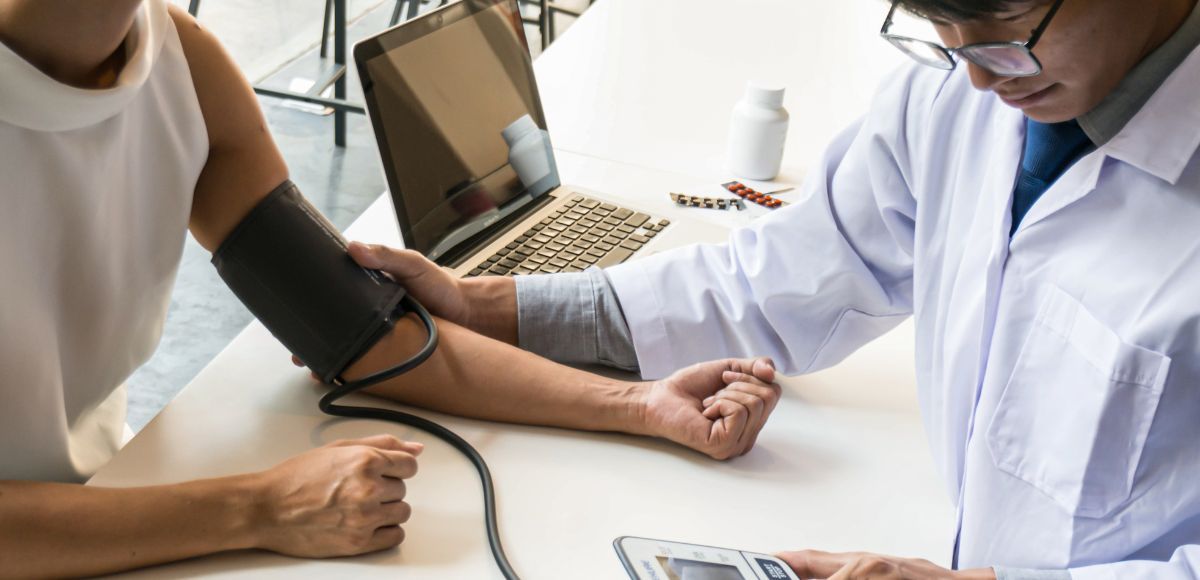 Doctor checking a patient’s blood pressure in a clinic with a cuff on the arm