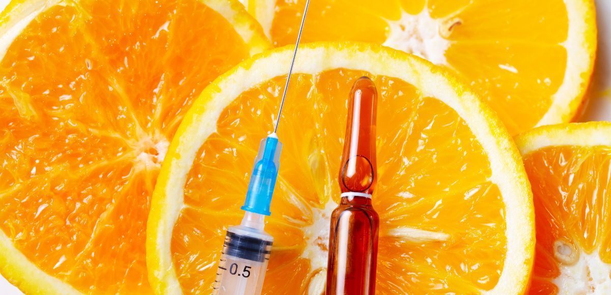 Orange slices with two syringes, one blue and one red, arranged in the center