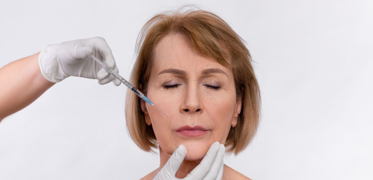Medical injector preparing a facial injection on a woman with eyes closed