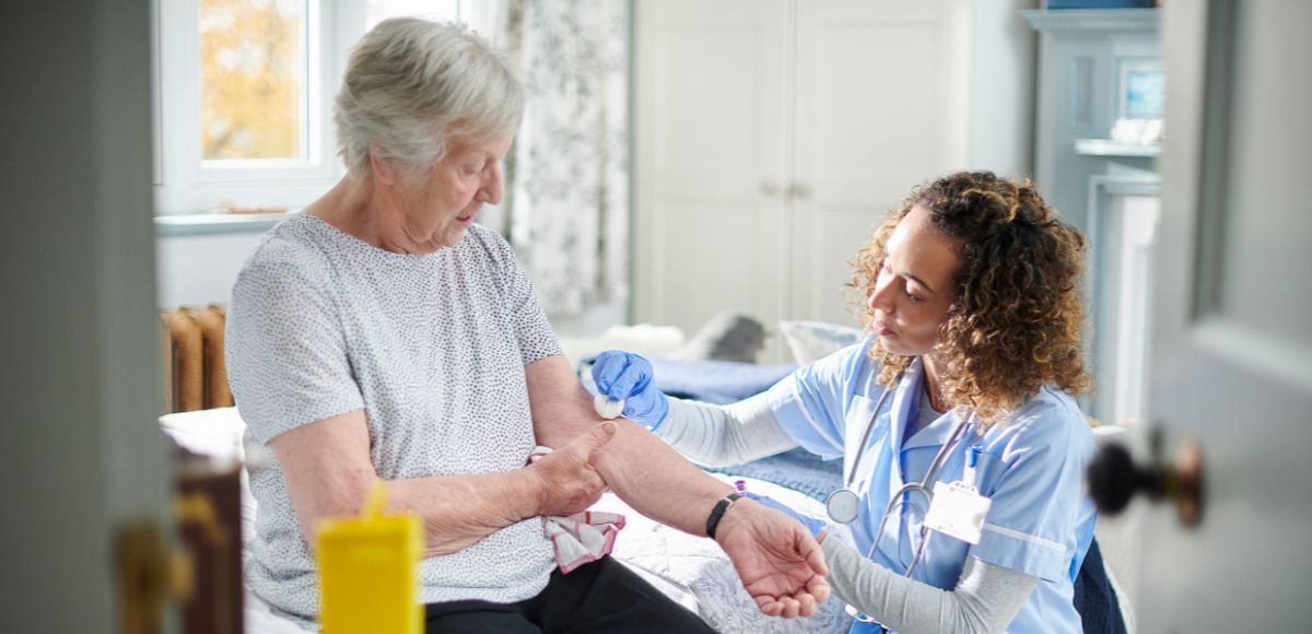 Nurse checking an older patient’s arm in a bright home setting