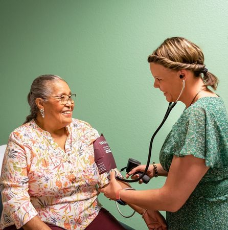 An older woman smiling as a healthcare professional checks her blood pressure