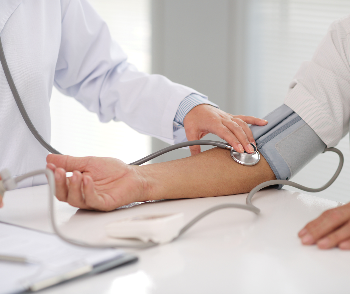 Doctor taking patient's blood pressure with stethoscope and cuff on arm.