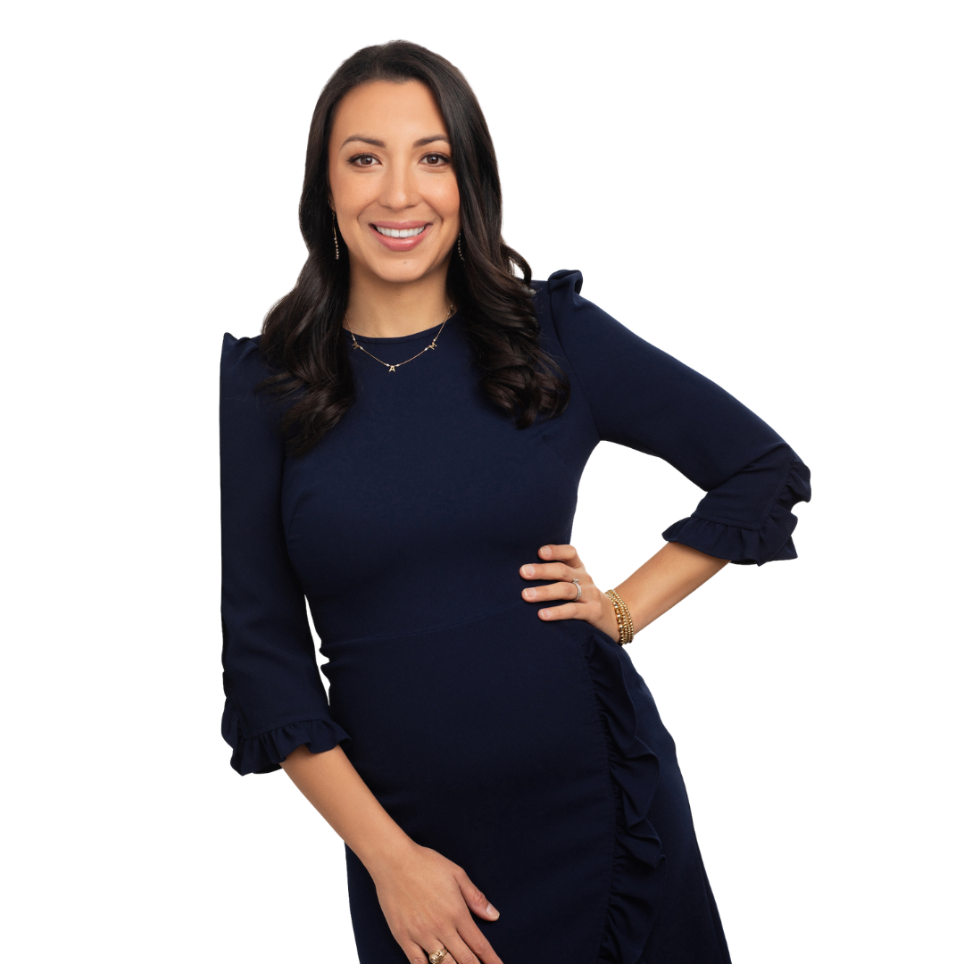 Woman in a navy blue dress, smiling with hand on hip.