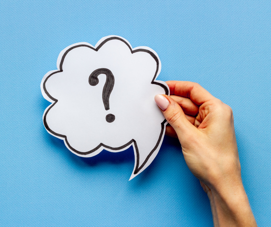 Hand holding a white speech bubble with a black question mark on a blue background.