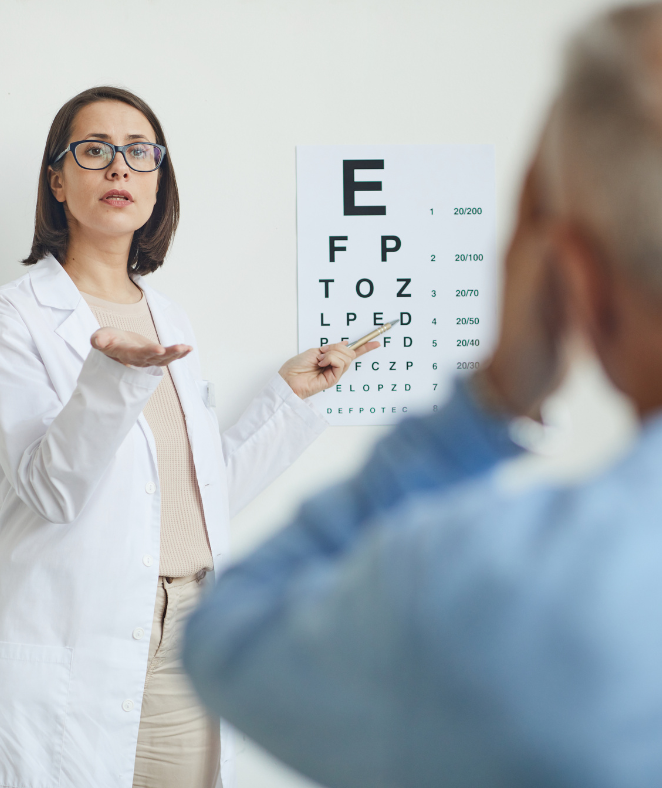 Optometrist pointing at eye chart, examining patient's vision in a clinic.