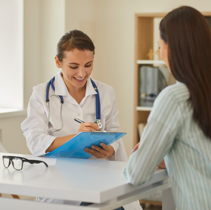 Doctor in white coat consults with a patient; doctor taking notes on a blue clipboard.