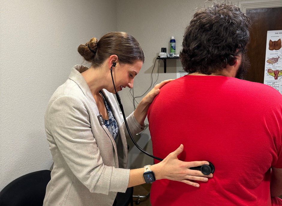 Doctor using stethoscope on a patient's back in a clinic.