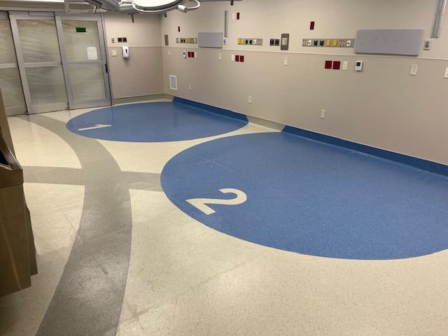 Hospital corridor with blue numbered floor circles and wall-mounted medical equipment￼