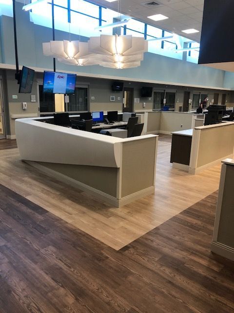 Empty modern office cubicle area with wood-look flooring, white partitions, and overhead lighting