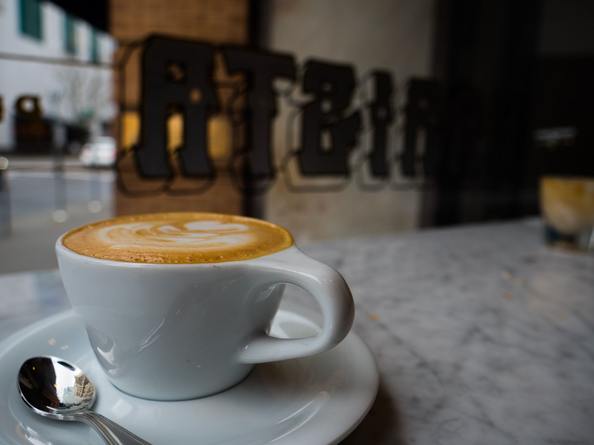 A cup of cappuccino on a saucer with a spoon
