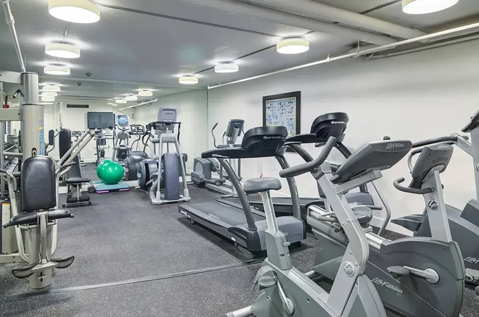 A gym filled with lots of exercise equipment and a large mirror.