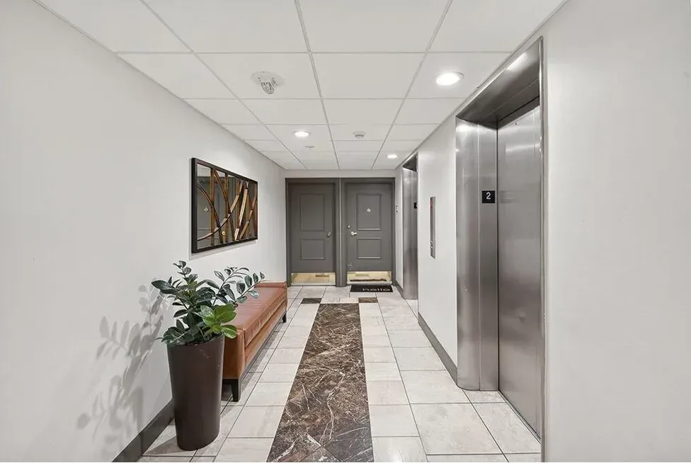 A hallway with two elevators and a bench in it