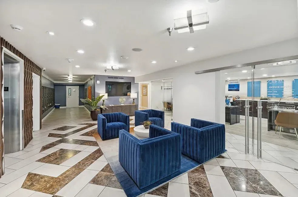 A lobby with blue chairs and a marble floor.