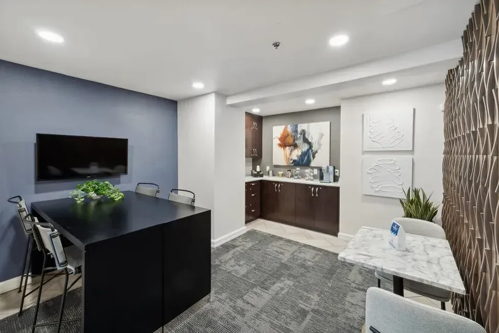 A room with a table and chairs and a television on the wall.