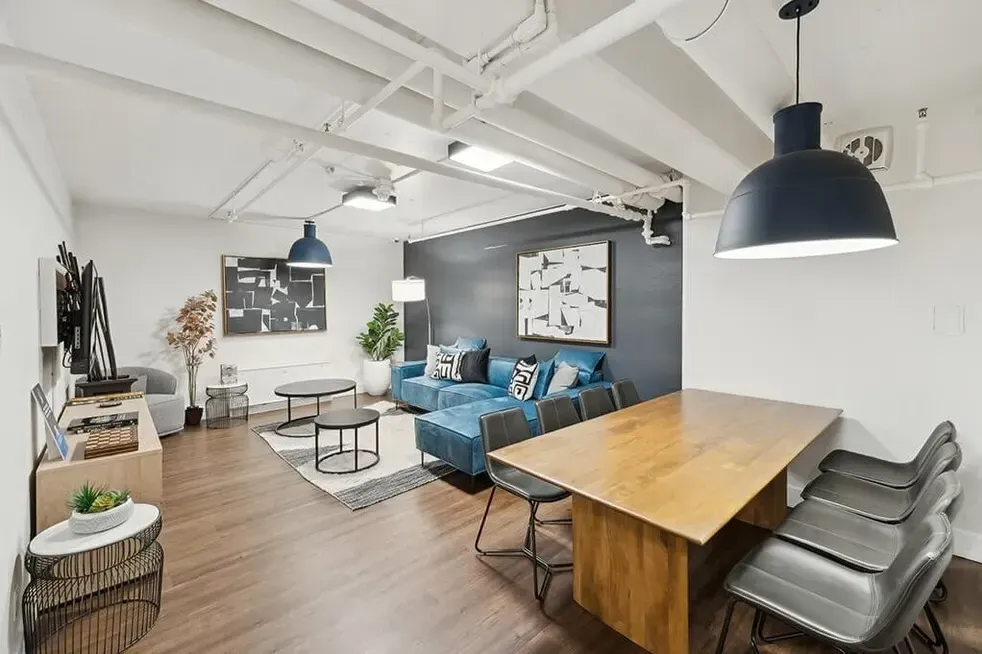 A living room with a table and chairs and a blue couch.