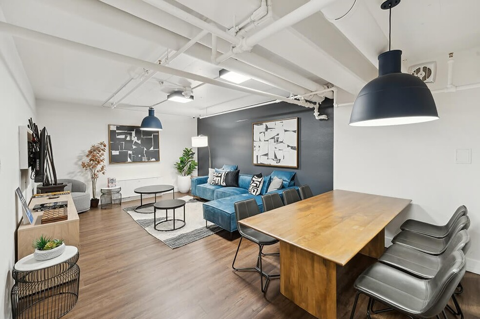 A living room with a table and chairs and a blue couch.
