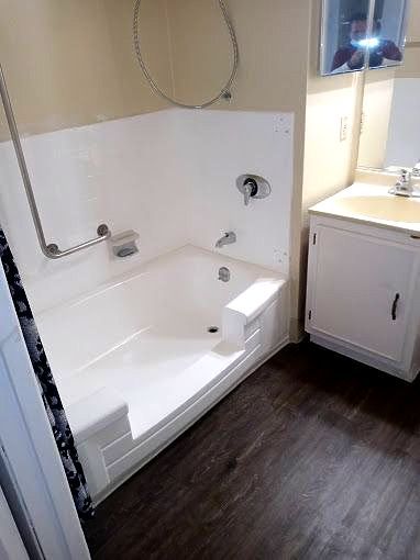 a bathroom with a tub and a window with shutters