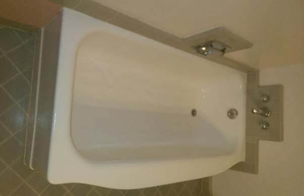 a white bathtub is sitting on a tiled floor in a bathroom .