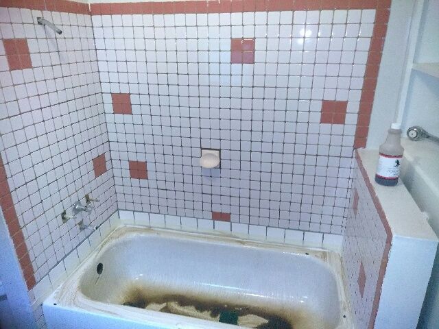 a bathtub in a bathroom with a bottle of acetone on the shelf