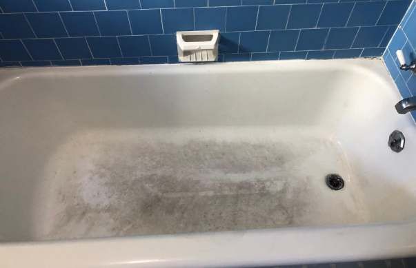 a white bathtub in a bathroom with blue tiles .