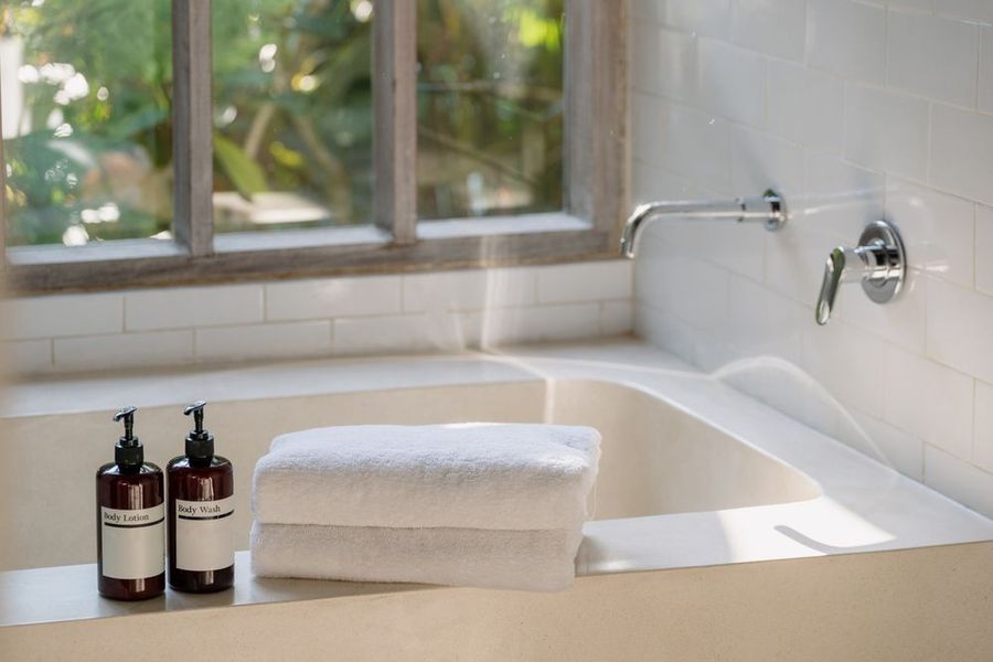 a bathtub with a wooden tray with candles and towels on it