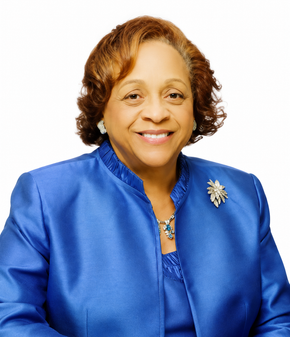 Smiling woman in a blue blazer with a silver brooch, posed against a white background