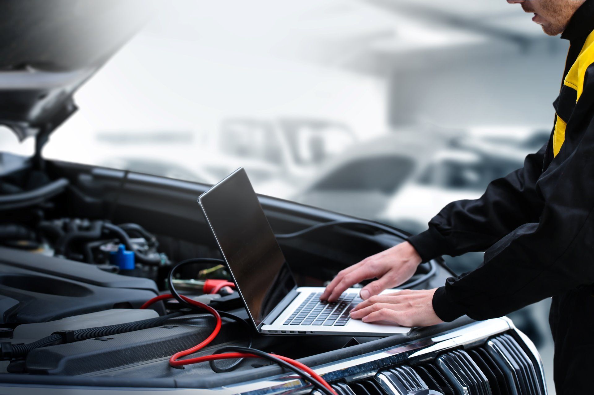 Mechanic using a laptop to diagnose a car engine in a garage