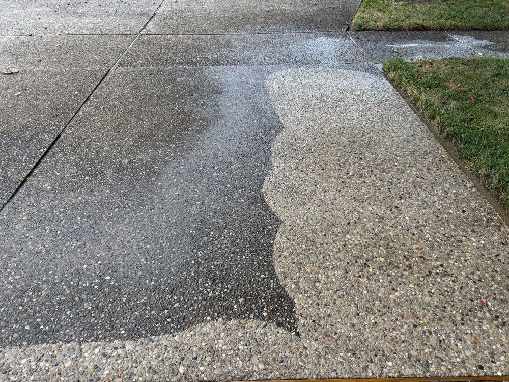 A concrete sidewalk is being cleaned with a pressure washer.