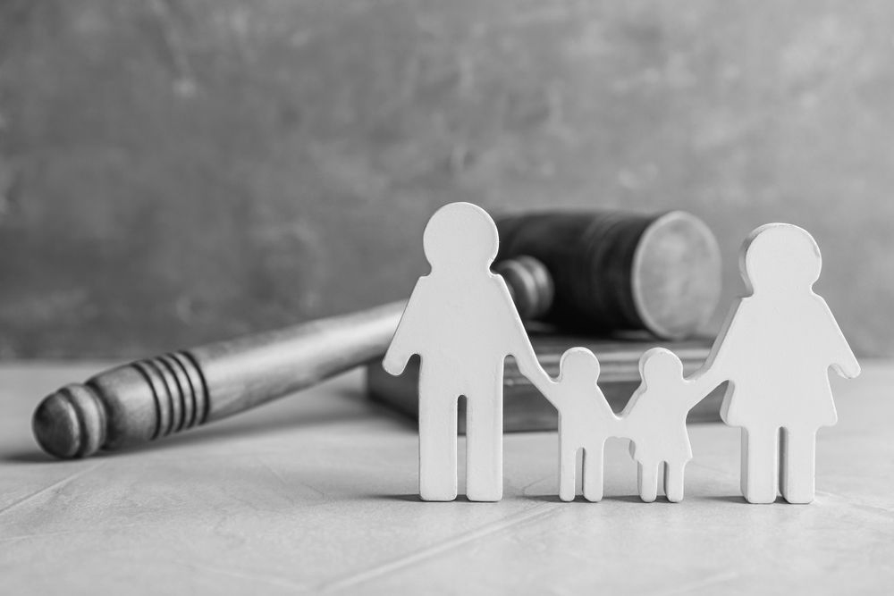 Paper family figures with a large gavel in the background, in grayscale. - ev law in Bundall, QLD
