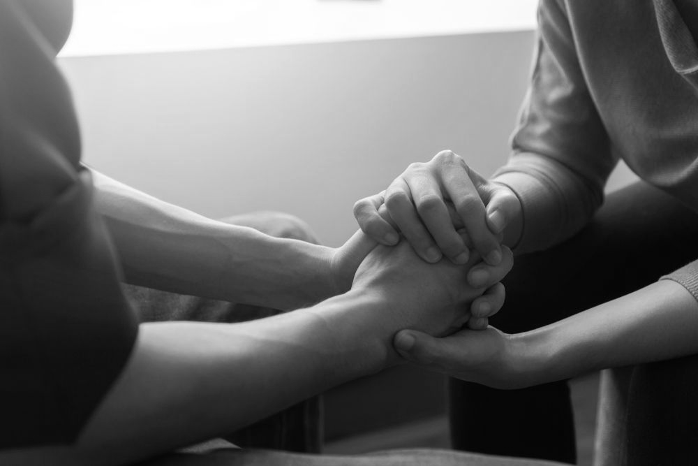 Two people holding hands in a black-and-white scene, seated close together - ev law in Bundall, QLD