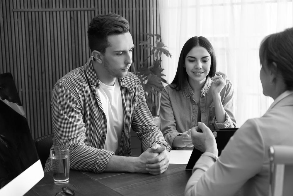 Three people in a meeting, seated around a table, talking in a bright office. - ev law in Bundall, QLD