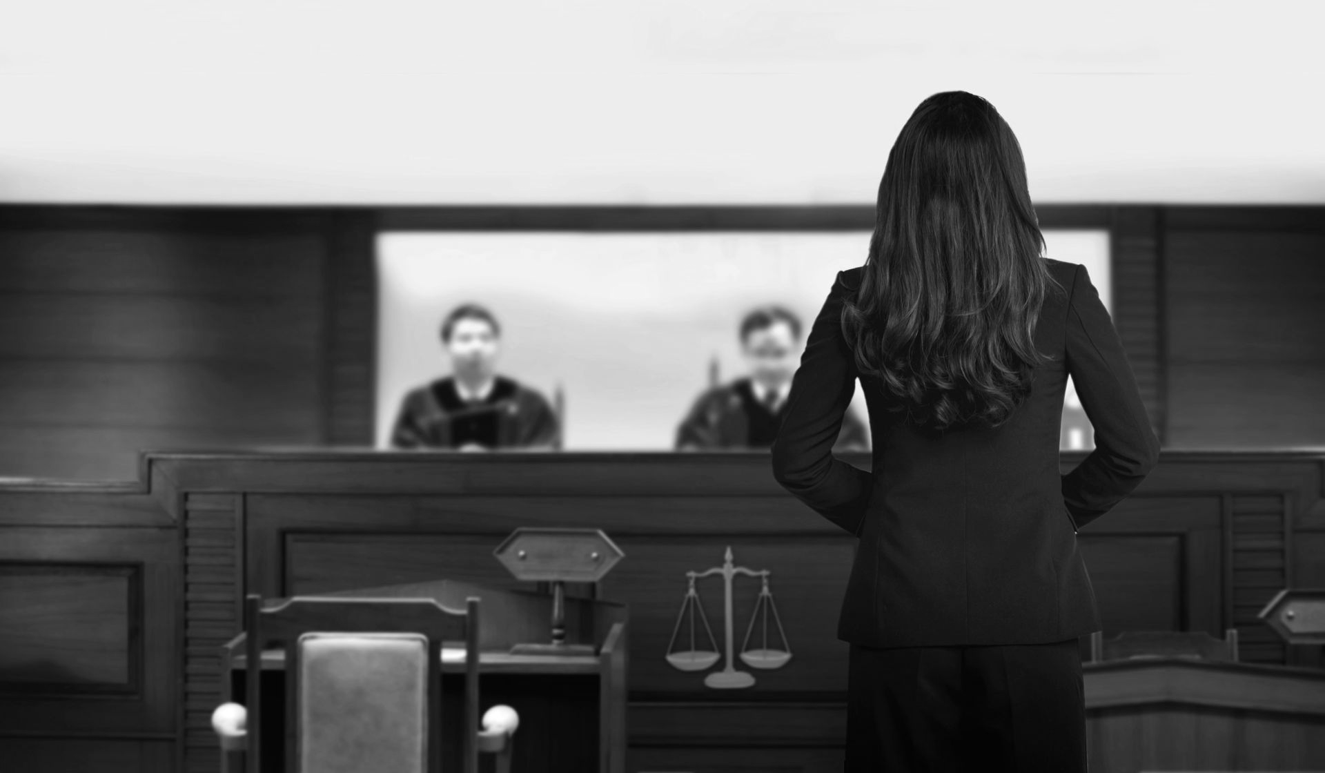 Woman standing before judges in a courtroom, facing the bench with legal symbols in view. - ev law in Bundall, QLD