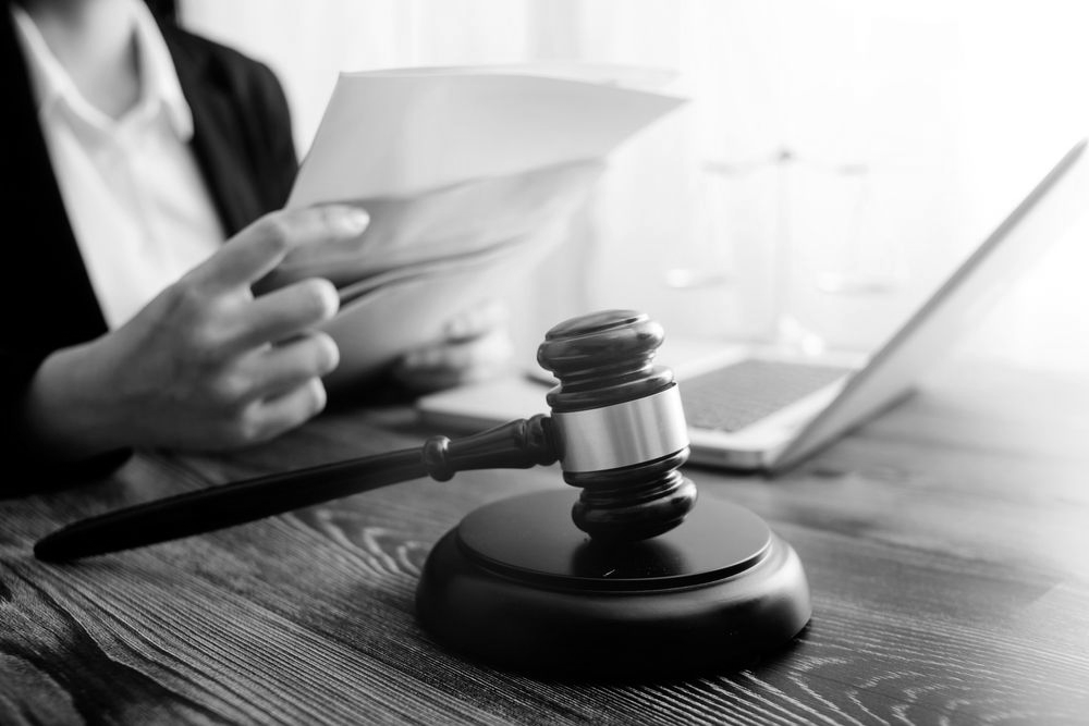 Lawyer holding documents beside a gavel and laptop on a wooden desk - ev law in Bundall, QLD