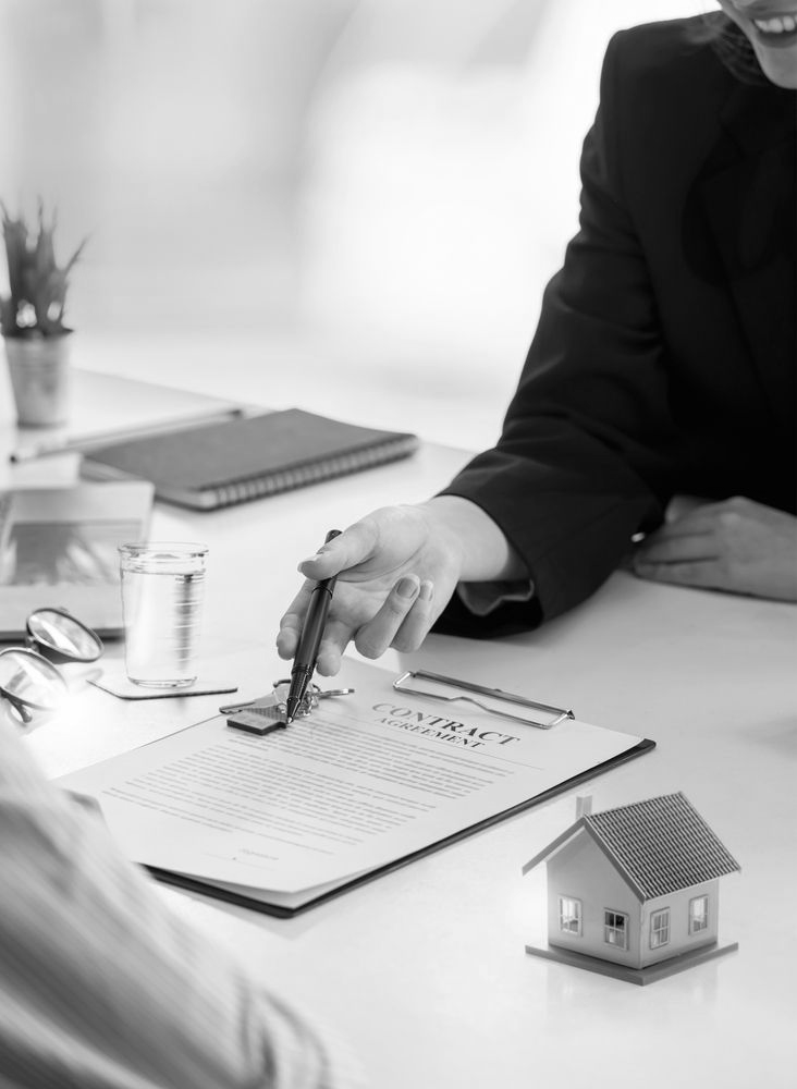Person stamping a document at a desk with a small house model nearby - ev law in Bundall, QLD
