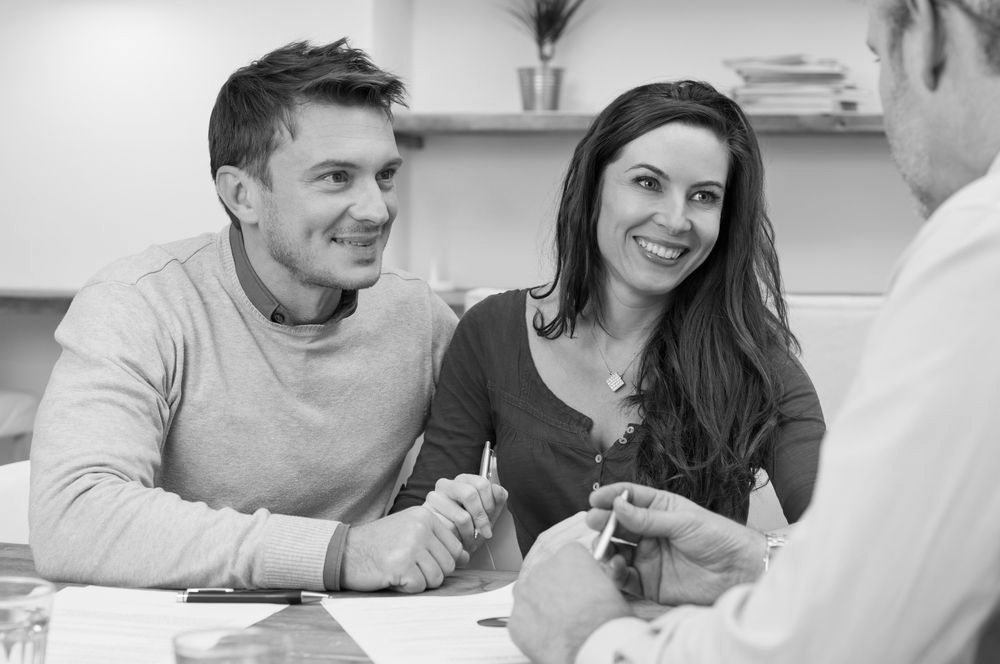 Three people smiling during a meeting, with papers on the table. - ev law in Bundall, QLD
